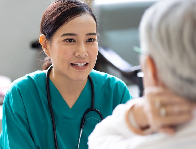 caregiver and elderly home care. Asian woman doctor or nurse talking with senior patient.